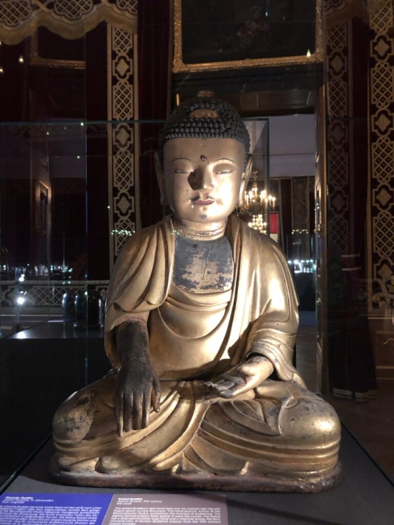 Eine sitzend Buddastatue mit einer auf dem Bein ruhenden und einer geöffneten Hand